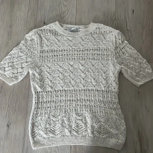Vit stickad tröja från Zara - Säljer en vit stickad tröja från Zara med ett detaljerat mönster. Tröjan har korta ärmar och en rund halsringning. Perfekt för en stilren look.
