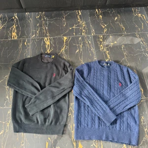 Tröjor från Polo Ralph Lauren - Säljer två stilrena tröjor från Polo Ralph Lauren. En svart och en blå, båda med det klassiska röda logotypbroderiet. Den blå tröjan har ett snyggt kabelstickat mönster. Perfekta för en avslappnad och stilren look. Är öppen för byten, skriv om ni är sugna att köpa båda eller bara en (byter helst mot något par skor, kan såklart ge pengar emellan) nypris på båda sammanlagd ligger kring 3000-4000kr  (s sitter som m)