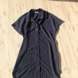 Mörkblå skjortklänning - Snygg mörkblå skjortklänning med knappar hela vägen ner. Perfekt för en avslappnad stil. Kortärmad med en klassisk krage.