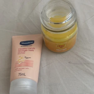 Handkräm och doftljus - Säljer en Vaseline Healthy Hands Stronger Nails handkräm i en 75 ml tub, perfekt för att stärka naglarna. Inkluderar även ett Chupa Chups doftljus med mangoarom i en glasburk, som ger en fruktig och uppfriskande doft.