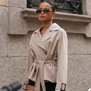 Beige trenchcoat från Nelly - Beige trenchcoat från Nelly med knappar och bälte i midjan. Köpt för 700 och aldrig använd!💕