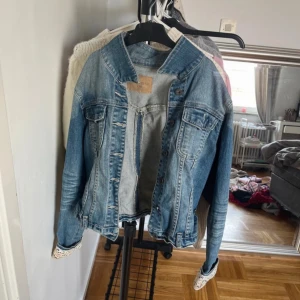 Blå jeansjacka - Snygg blå jeansjacka med klassisk design och knappar framtill. Perfekt för en avslappnad stil. Jackan har långa ärmar och två bröstfickor med lock.