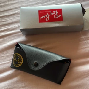 Svarta solglasögon från Ray-Ban - Säljer ett par klassiska svarta solglasögon från Ray-Ban. De har en stilren design med mörka linser och kommer med ett snyggt fodral. Perfekta för soliga dagar!