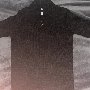 Mörkgrå stickad tröja från Pier One - Snygg mörkgrå stickad tröja från Pier One med en quarter zip. Perfekt för kyliga kvällar. Är endast använd 2 gånger.