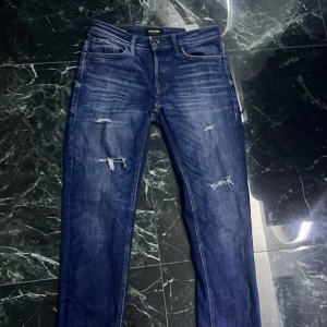 Blå jeans från Jack & Jones med slitningar -  Snygga mörkblå slimfit jeans från Jack & Jones med slitningar. Nypris 899kr