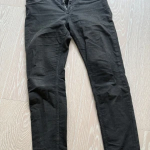 Svarta manchester byxa från Whyred strl: 30/32 - Snygga svarta byxor från Whyred med dragkedja och knapp framtill. Byxorna har en klassisk design med normal passform och är perfekta för en stilren look.