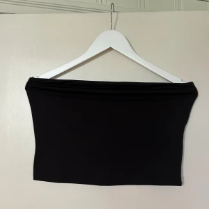 Svart tubtopp från Vero Moda - Säljer en stilren svart tubtopp från Vero Moda. Perfekt för att matcha med olika outfits. Toppen är enkel och elegant, vilket gör den till ett mångsidigt plagg i garderoben.