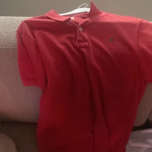 Röd pikétröja från Morris - Säljer en snygg röd pikétröja från Morris. Tröjan har en klassisk krage med knappar och en liten broderad logga på bröstet. Perfekt för en stilren look.