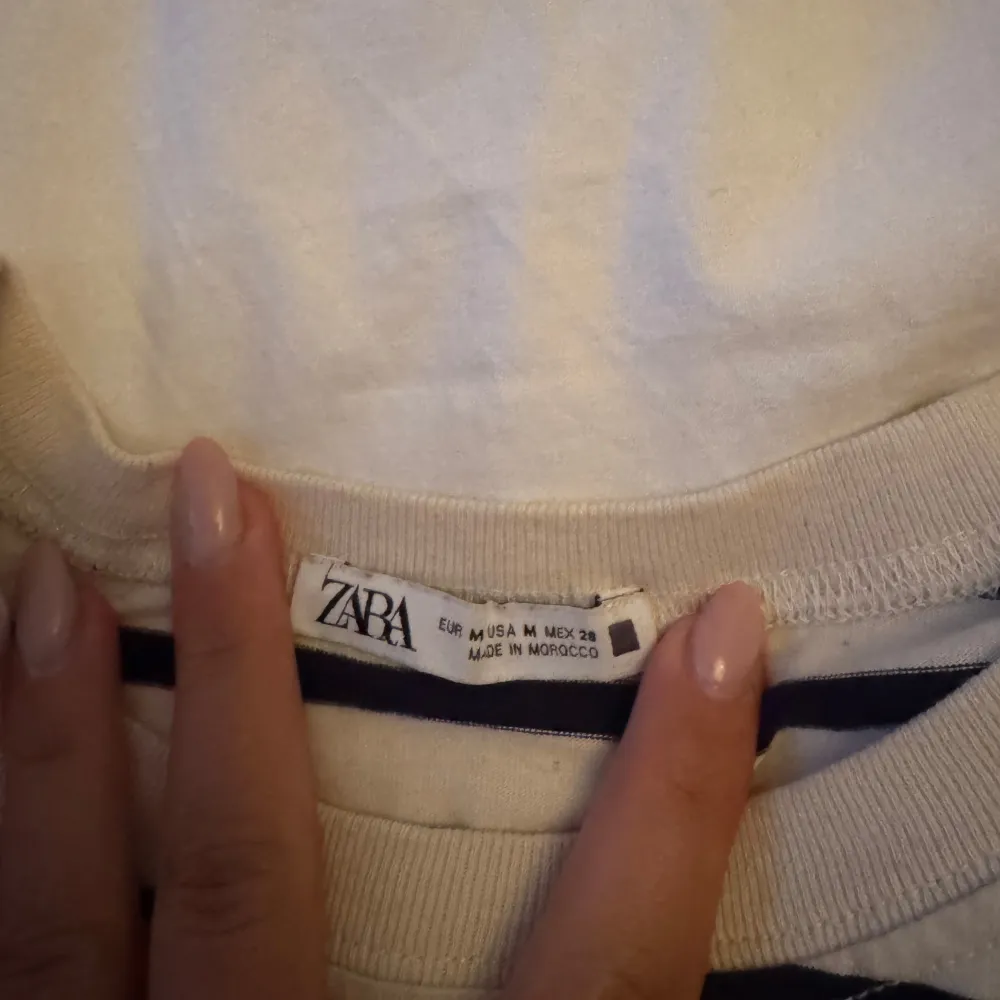 Säljer en randig topp från Zara i svart och vit. Toppen har korta ärmar och en volangdetalj vid midjan som ger en fin form. Perfekt för en avslappnad stil.. Yläosat.