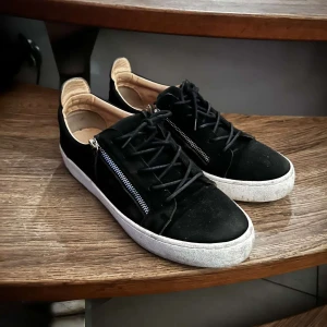 Giuseppes zanotti skor - Snygga svarta sneakers från giuzeppi med dragkedja på sidan och snörning. Skorna har en vit sula och är tillverkade i mocka för en stilren look. Perfekta för en trendig vardagsstil. 