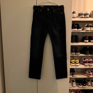 Mörkblå jeans från Levi's - Snygga mörkblåa 511 jeans från Levi's med klassisk femficksdesign och knappgylf. Perfekta för en stilren look. Passar bra till både vardag och mer uppklädda tillfällen.byxorna är i mycket bra skick. Byxorna är i storlek 30-