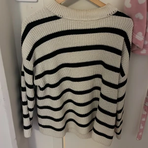 Randig stickad tröja från H&M - Säljer en snygg randig stickad tröja från H&M i svart och vit. Tröjan har en klassisk design med långa ärmar och en bekväm passform. Perfekt för kyligare dagar!