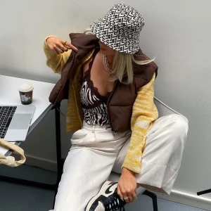 Brun dunväst från Russel Rainey  - Säljer en snygg brun dunväst från Russel Rainey. Västen har en dragkedja framtill och en hög krage för extra värme. Perfekt för lager-på-lager under kyligare dagar. Passar bra till både casual och mer uppklädda outfits.