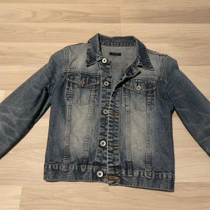 Blå jeansjacka - Säljer en blå jeansjacka med knappdetaljer och fickor! Obs, väldigt urtvättad