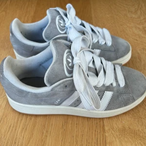 Gråa Addidas Campus  - Gråa addidas Campus jag inte använt så mycket. De har ett litet hål vid hälen som syns på sista bilderna men de känns helt som vanligt!