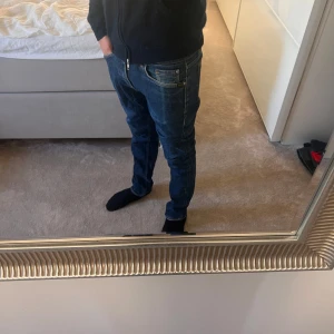 Mörkblå jeans från Tiger of Sweden - Snygga mörkblå jeans från Tiger of Sweden med klassisk femficksdesign och raka ben. Jeansen har en stilren look med diskreta sömmar och är tillverkade i ett mjukt bomullstyg med lite stretch för extra komfort. Storlek 29/32