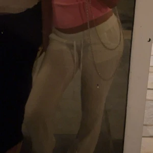 Vita vida linnebyxor med snörning - Säljer ett par tunna, vita linnebyxor med bred resår i midjan och snörning framtill. Byxorna har raka, vida ben och bakfickor. Perfekta för en chill och luftig stil under varma dagar.