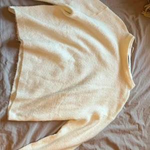 Krämvit stickad tröja med rund hals - Mysig krämvit stickad tröja med rund halsringning och långa ärmar. Tröjan har en enkel och clean design med ribbade muddar vid ärmslut och nederkant. Perfekt för lager-på-lager och chill dagar.