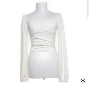 Vit långärmad blus med puffärm - Supersnygg vit blus med långa puffärmar och lätt rynkade detaljer vid axlarna,tröjärmarna och i sidan. Toppen har en figurnära passform och söt v-ringning. Perfekt att styla med jeans eller kjol för en trendig look. Liten fläck på ärmen som kanske skulle kunna försvinna i tvätten,aldrig använd själv då den är för liten och jag brukar ha S så kanske lite liten i storlek. Köpt på Sellpy.