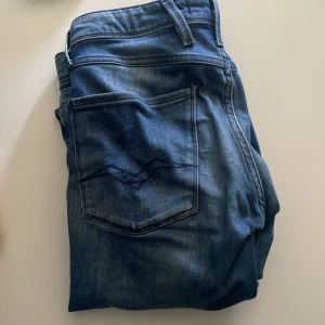 Replay Anbass blå jeans - Säljer ett par Replay Anbass jeans i klassisk blå tvätt med snyggt slitna detaljer. 31/32, bra skick 👍