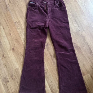 Vinröda manchesterbyxor Stallion - Snygga vinröda manchesterbyxor från Stallion med klassisk femficksdesign och bootcut-ben. Byxorna har hällor för bälte, dragkedja och knapp framtill samt märkesskylt bak. Perfekta för dig som gillar retrovibbar och mjukt material.