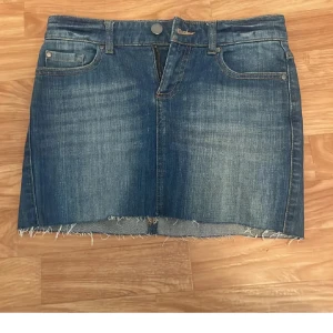 Jeanskjol - Snygg blå jeanskjol från Bondelid med rå kant nertill och klassiska femficksdetaljer. Kjolen har bälteshällor, knapp och dragkedja framtill samt två bakfickor. Perfekt för dig som gillar en avslappnad och trendig stil. Midjemått rakt över 36 cm
