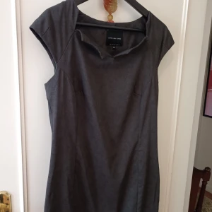 Mörkgrå klänning Bitte Kai Rand - Snygg mörkgrå kortklänning från Bitte Kai Rand med cool krage och minimalistisk design. Klänningen har korta ärmar och figurnära passform, perfekt för dig som gillar stilren look. Materialet känns mjukt och följsamt.