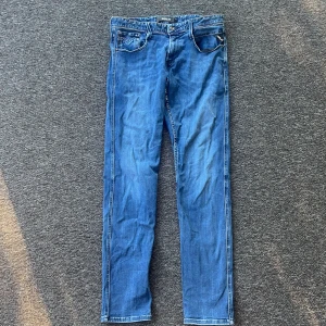 Blå Replay jeans slim fit W30 L32 - Säljer ett par blå Replay jeans i slim fit med klassisk femficksdesign och snygga kontrastsömmar. Jeansen har normal midja och raka ben, tillverkade i mjukt denimtyg som sitter skönt. Perfekta för dig som gillar stilrena och bekväma jeans.