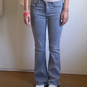 Grå bootcut jeans - Säljer ett par ljusgråjeans med bootcut-modell och klassisk femficksdesign.  Braskick. Jeansen har normal passform och är tillverkade i mjukt denimtyg som ger en avslappnad vibe. Perfekta för dig som gillar retrostil och vill ha ett par snygga jeans med lite utsvängda ben.