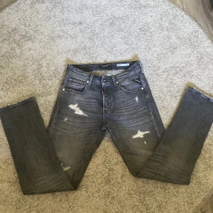Replay Grover grå slitna jeans / helt nya - Säljer ett par Replay Grover jeans i grå tvätt med slitna detaljer och snyggt mönstrade bakfickor. Jeansen har rak passform och klassisk femficksdesign. Perfekta för dig som gillar en lite ruffare streetstil.