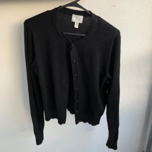 Svart basic kofta med knappar - En klassisk basic svart kofta med rund halsringning och knappar framtill. Långärmad och i mjuk ull och bomull som passar perfekt till lager-på-lager. Använd en gång då jag behövde en svart kofta men nu efter de använder jag den aldrig. Den är M men jag som har S/M är den mer som S i storleken men ärmarna är lite längre så dom är ca M/L (men de är ju bara skönt tycker jag.