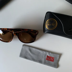 Ray-Ban Wayfarer brun leopardmönstrad - Snygga Ray-Ban Wayfarer solglasögon med bruntonade glas och leopardmönstrad båge i plast. Klassisk modell som ger cool vibe. Kommer med originalfodral i svart läder och putsduk med Ray-Ban-logga.