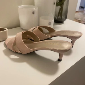 Ljusrosa sandaler med låg klack Lascana - Snygga ljusrosa sandaler från Lascana med korsade remmar och låg klack. Skorna har öppen tå och en stilren design som passar perfekt till sommarens outfits. Materialet är mjukt och ger en lyxig känsla.