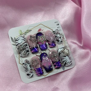 ZebraRoyale (S);Medium Square - Set gelé lösnaglar i lila, rosa och svartvitt zebramönster. Naglarna har coola 3D-dekorationer som stjärnor, kors och små pärlor i silver. Mix av glansiga, vissa naglar har swirl-mönster och metallic-effekt. Kommer i storek S: 15 mm, 11,5 mm, 12 mm, 11 mm, 9 mm