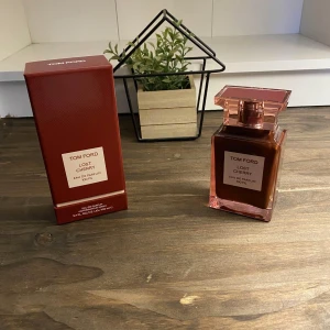 BUD! Tom Ford Lost Cherry EdP 100 ml - Tom Ford Lost Cherry Eau de Parfum 100 ml med lyxig röd glasflaska och matchande röd kartong. Doften är känd för sina söta körsbärstoner och exklusiva känsla. Flaskan har en fyrkantig form och tydlig etikett framtill. Perfekt för dig som gillar unika och djärva dofter. TAR BUD! Är enbart öppnad och testad, nypris ca 5.000kr.