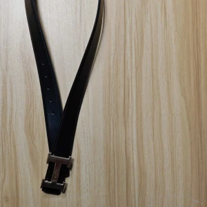 Svart H bälte med guldspänne - Snyggt svart bälte med ikoniskt H-spänne i guldmetall. Bältet är gjort i äkta skinn och har en stilren, klassisk design som lyfter vilken outfit som helst. Levereras med original orange -box.