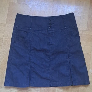 Svart jeanskjol från H&M - Snygg svart jeanskjol från H&M med fickor fram och bak samt dekorativa knappar framtill. Kjolen har kort längd och coola slitsar bak för extra rörelsefrihet. 🩷 Färg stämmer bäst överens med sista bilden