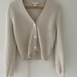 Beige kofta från Monki med knappar - Supergullig beige kofta från Monki. Den är ganska nopprig som man kan se på bilden men annars inga fel💕