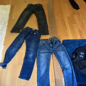 Tre par jeans i olika blå nyanser - Säljer tre par jeans i olika blå och svart tvätt. Alla har klassisk femficksdesign och raka ben. Ett par är mörkblå, ett par är ljusare blå med slitningar och ett par är svartgrå. Perfekta för dig som gillar en avslappnad och tidlös stil endast 100 kr för alla tre.