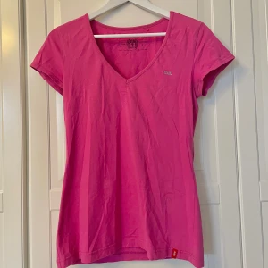 Rosa v-ringad t-shirt från edc - Snygg rosa t-shirt från edc med v-ringning och korta ärmar. Gjord i mjuk bomull och har ett litet glittrigt edc-logo på bröstet. Perfekt för dig som gillar färg och enkel stil.