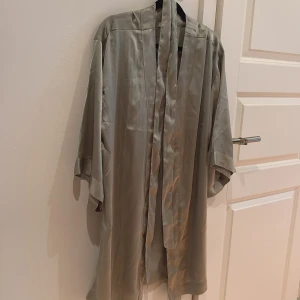 Kimono  - Fin kimono i sage green  från Bubbleroom i glansigt satinliknande material. Modellen är loose fit med trekvartsärmar och har ett bälte i midjan för att knyta. Endast använd 1 gång. Behöver strykas. 