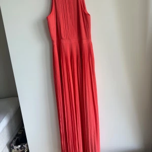 Maxiklänning  - Maxiklänning från Mint&Berry med plissering och hög halsringning som stängs med knappar och dragkedja i ryggen. Endast använd 2 gånger.