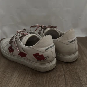 Zadig voltaire skor  - Vita sneakers med röda hjärtan på sidan och snören med röd text. Skorna är ifrån Zadig, box och påse följer med när man köper skorna💕skriv om ni har några frågor! Priset är diskuterbart, bara att höra av er!💕Dom är stolek 41 men skulle säga att de både passar 40-41💕priset är diskuterbart och accepterar alla rimliga förslag!🥰säljer då jag har för mycket skor, skorna är köpta för 3500. Skriv innan ni köper så aktiverar jag ”köp nu”💓💓