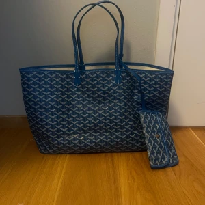 Blå shoppingväska med mönster - Säljer en ikonisk blå shoppingväska. Väskan har långa handtag, matchande avtagbar innerficka och är tillverkad i slitstarkt syntetmaterial med skinn-detaljer. Perfekt för dig som vill sticka ut med en lyxig och rymlig väska.