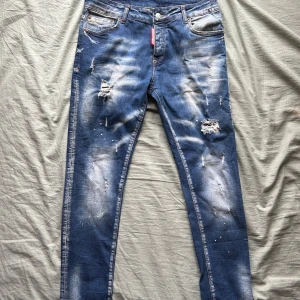 Dsquared2 jeans - Snygga blå jeans från Dsquared2 med slitna detaljer och en cool tvättad look. De har en knappgylf och klassisk femficksdesign. Perfekta för en avslappnad stil med en touch av edge.