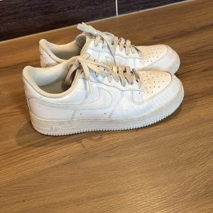 Nike Air Force - Säljer ett par klassiska vita Nike Air Force sneakers. De har en stilren design med snörning och perforerade detaljer på ovansidan för ventilation. Perfekta för en casual look.