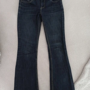 Mörkblå bootcut jeans från Lindex - Snygga mörkblå bootcut jeans från Lindex med kontrastsömmar. Perfekta för en avslappnad stil! . De har en knapp och dragkedja framtill. Passar någon som är ca 155 och brukar bära XS. 