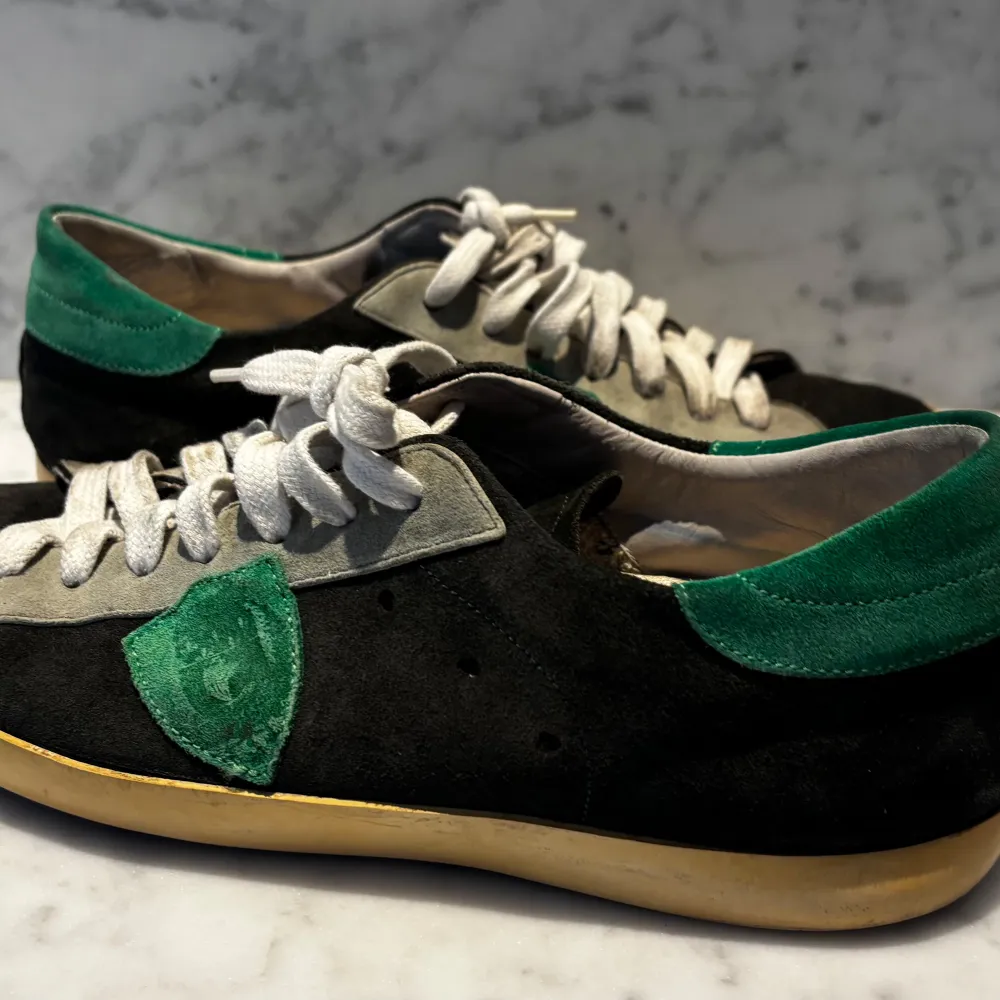 Snygga sneakers i svart mocka med gröna detaljer och vita snören från Philippe Model. Skorna har en klassisk design med en bekväm sula och en stilren look. Perfekta för en avslappnad stil.. Kengät.