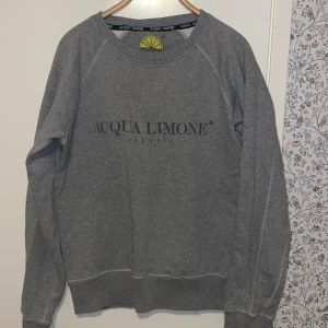 Grå sweatshirt från Acqua Limone - Säljer en grå sweatshirt från Acqua Limone med deras klassiska logga tryckt på både fram- och baksidan. Tröjan har långa ärmar och en rund halsringning. Perfekt för en avslappnad stil. Tröjan är i mycket bra skick, och köpt för cirka 1150. Skriv vid funderingar!