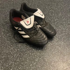 Adidas Copa fotbollsskor - Säljer ett par svarta Adidas Copa fotbollsskor med vita detaljer och klassisk snörning. Skorna har en robust sula med dobbar för bra grepp på planen. Perfekta för fotbollsträning och matcher.